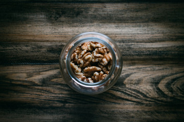 masjon jar with walnuts on wooden table in the middle