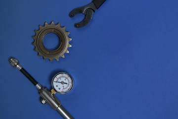 Fototapeta na wymiar Manometer, sprocket and wrench on blue background, flat lay with space for text. Bicycle tools