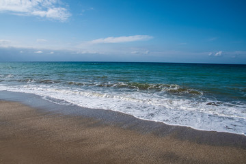 Mediterranean sea at sunset. Waves break on the sandy shore, sea foam. Natural background