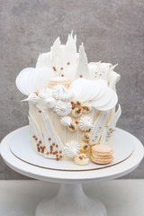 Modern elegant grey cake with white chocolate, waffle paper, macaroons and meringues.