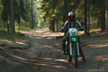Fototapeta premium off-road motorcycle trip in the forest, beautiful girl, feminism, sport, brutality, motorcyclist equipment, motorcycle driver, concept, active lifestyle, enduro