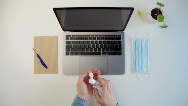Modern workspace, a male uses hand sanitizer to disinfect his hands at workplace
