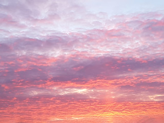 A view of the sky with thick clouds at sunset in bright orange and purple tones. Concept landscape, nature, background.