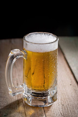 Light frothing beer in a glass, on an old background.