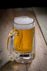 Light frothing beer in a glass, on an old background.