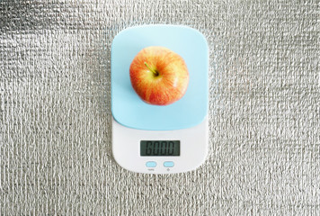 Red glossy apple on scales with GOOD message, on silver background. Template healthy food with eco fruit. Closeup