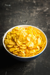 Tasty crispy corn flakes in bowl on the rustic background. Selective focus. Shallow depth of field.