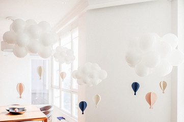 Compositions of white inflatable balls in the form of clouds against the background of stylish interior of the room.