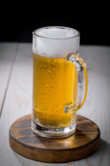 Light frothing beer in a glass, on an old background.