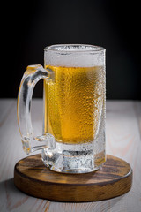 Light frothing beer in a glass, on an old background.