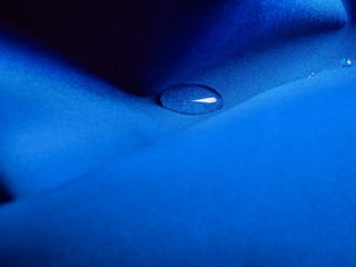 Blue waterproof fabric with drop of rain close up