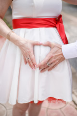 hands of the bride and groom on a white wedding dress