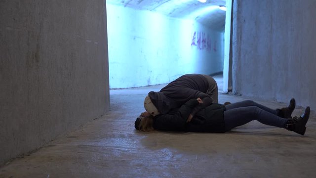 Earth after zombie apocalypse. Living dead attacked girl and eats her brain to satisfy hunger and spread the epidemic. Woman lying in convulsions on ground in corridor of underpass or shelter bunker.