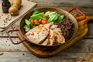 Turkey with black rice on old wooden table