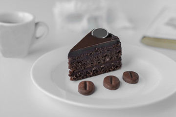 A slice of chocolate cake on a white plate. Chocolate brownie on a white background, close-up.