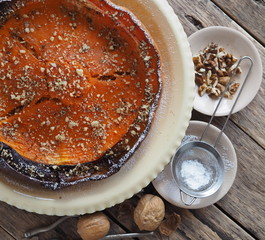 Pumpkin Background. Baked pumpkin sprinkled with ground walnuts, on a wooden ancient background with ingredients. View of a serkha.Place for text.