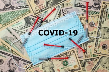Medical viel laid on US dollars. Syringes are placed on the veil. On veil inscription dangerous virus COVID-19.