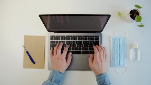 Modern workspace, a male using a laptop during coronavirus quarantine 