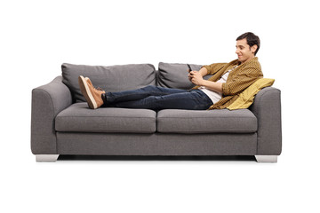 Relaxed young man lying on a sofa with a mobile phone