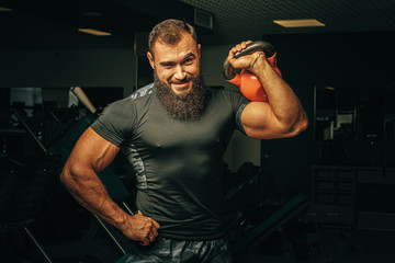 Bodybuilder doing exercises with dumbbells in a dark gym - obrazy, fototapety, plakaty