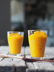 Two glasses of natural smoothie, juice, cocktail, made at home from the pulp of homemade pumpkin, on a blurred background of the kitchen.