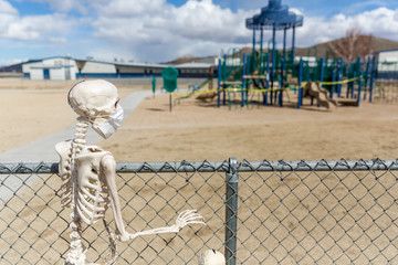 Skeleton behind fence looking at an empty closed park on a nice day
