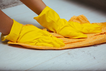 The girl in yellow gloves wash the dusty white floors yellow cloth