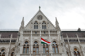 Building of the Hungarian Parliament Orszaghaz in Budapest, Hungary. The seat of the National Assembly. House built in neo-gothic style. Waving flag of Hungary on the house. Hungarian concept