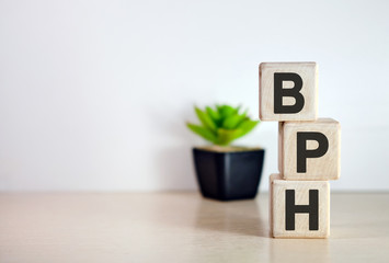 BPH - text on wooden cubes, on wooden background. Flower in a pot