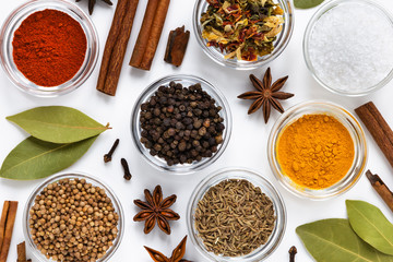 set of assorty colorful spices and herbs in bowls on white background, flat lay, top view