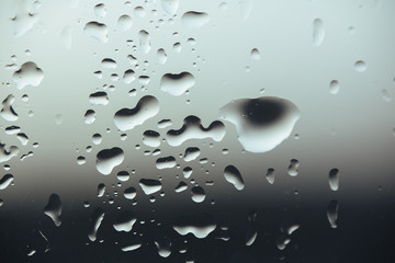 Macro pure rain drops on the glass against a cloud gray background