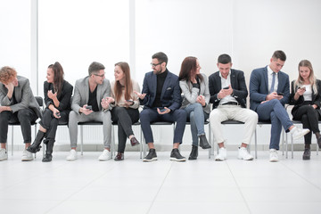 group of diverse young business people looking at their smartphone screens.
