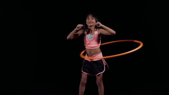 A little asian girl thumbs up practicing hula-hoop
