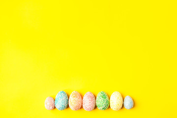 Pastel eggs on yellow background down side with space for text. Happy easter.
