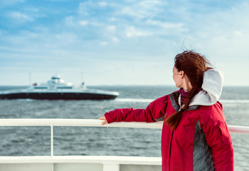 the girl on the ferryboat looks towards the sea, where the liner floats
