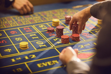 Close-up of hands with chips for gambling on a casino roulette table.