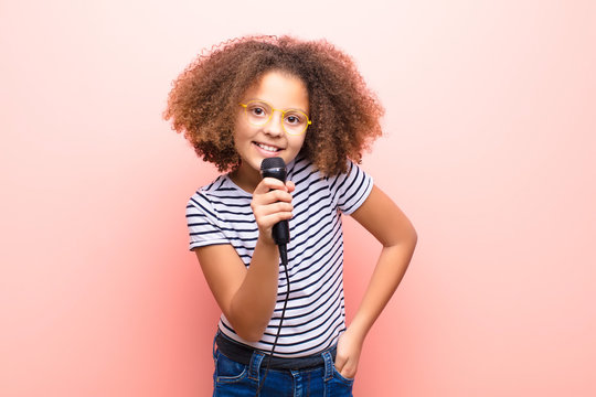 african american little girl  against flat wall with a microphone