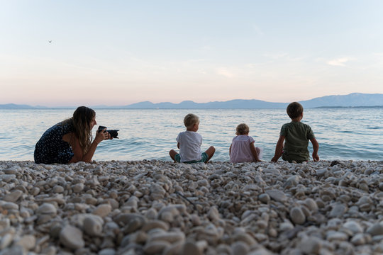 Mother taking photos of her kids on the beach