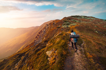 Fototapeta premium Hiking trough epic mountain landscape with a big backpack, exploring and feeling the freedom of nature