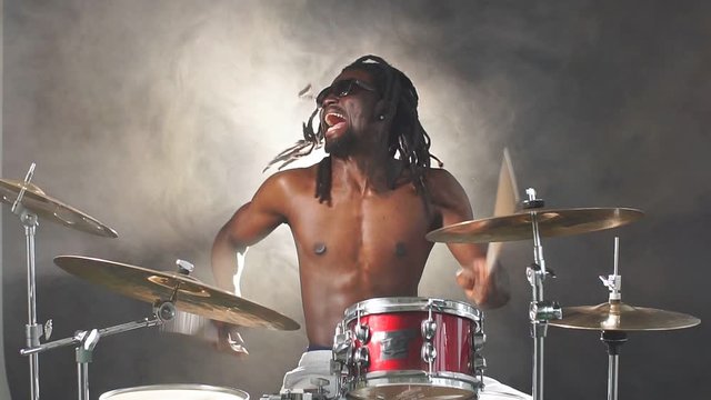 Portrait of african man performing music with use of drum set, handsome black naked man
