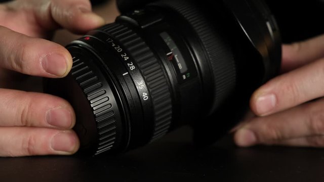 A man's hand turns the focus wheel on the lens. Close up.