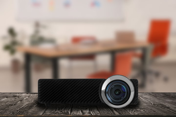 Modern video projector and blurred conference room interior on background
