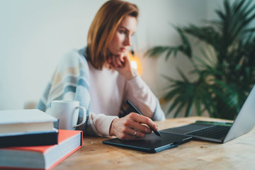 Home Office, Young graphic designer working remotely from home sitting in cozy blanket at table in...
