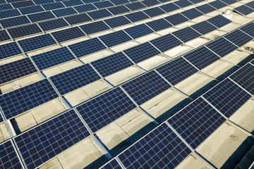 Obraz premium Aerial view of many photo voltaic solar panels mounted of industrial building roof.