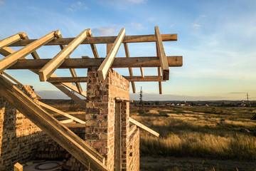 Private residential house with wooden roof frame structure under construction. Unfinished brick...