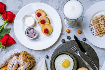 Breakfast on the table: cheesecakes, fried eggs, pancakes and coffee