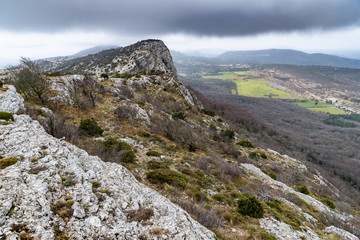 Fototapeta na wymiar The mountain over grotto of Mary Magdalene at cloudy weather, clouds over a valley, a dry grass