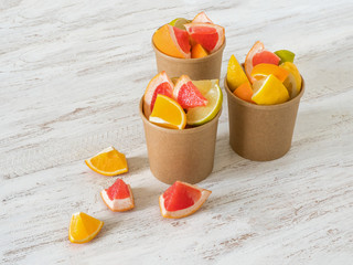 Fototapeta na wymiar Citrus slices in a environmental paper cups. Vitamin C drink. Strengthening the immune system concept