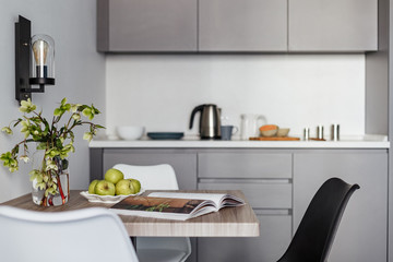 wooden square dining table with a vase with flowers magazine and I blocks on the background of dishes and a teapot