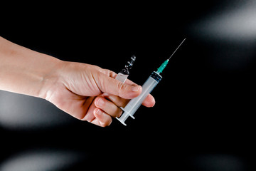 Syringe and pharmaceutical vial in human hands